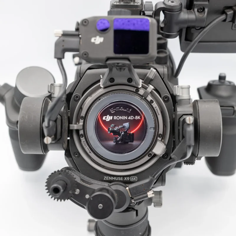 A close-up, front-facing view of a DJI Ronin 4D-8K cinema camera with a Zenmuse X9-6K gimbal system, featuring a lens mount and a small display screen.