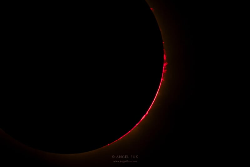 A solar eclipse shows the dark silhouette of the moon against the sun, with a thin red ring of light and solar prominences visible along the edge.