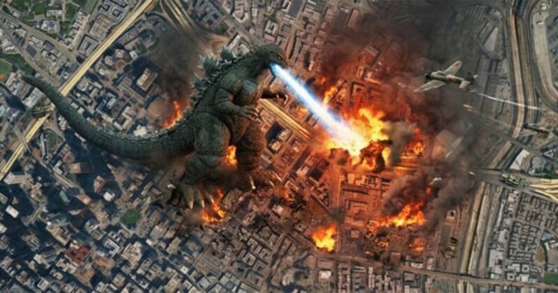 Godzilla stands in the center of a burning city, firing a blue atomic breath beam at the ground while a fighter plane flies nearby.
