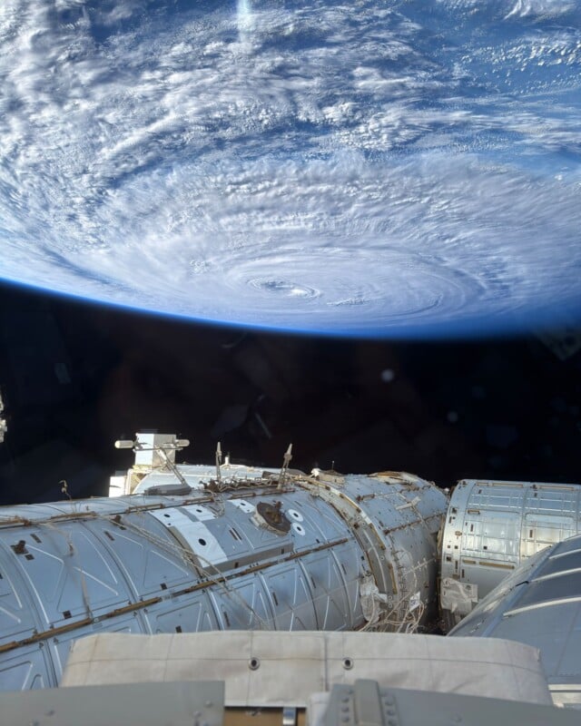 A view from the International Space Station looking down at a large, swirling hurricane over Earth's horizon.