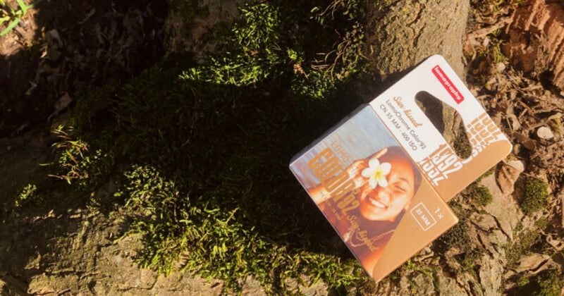 A box of Lomography LomoChrome Color '92 35mm film rests on a mossy tree trunk.