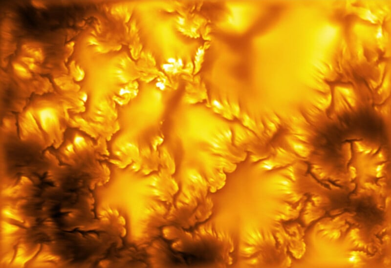 Abstract, swirling patterns of bright yellow and orange light contrast with deep, dark shadows, resembling liquid fire.