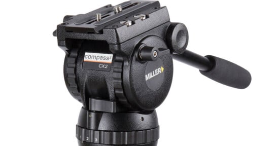A black Miller Compass CX2 fluid tripod head with a pan handle, mounting plate, and numbered adjustment dials.