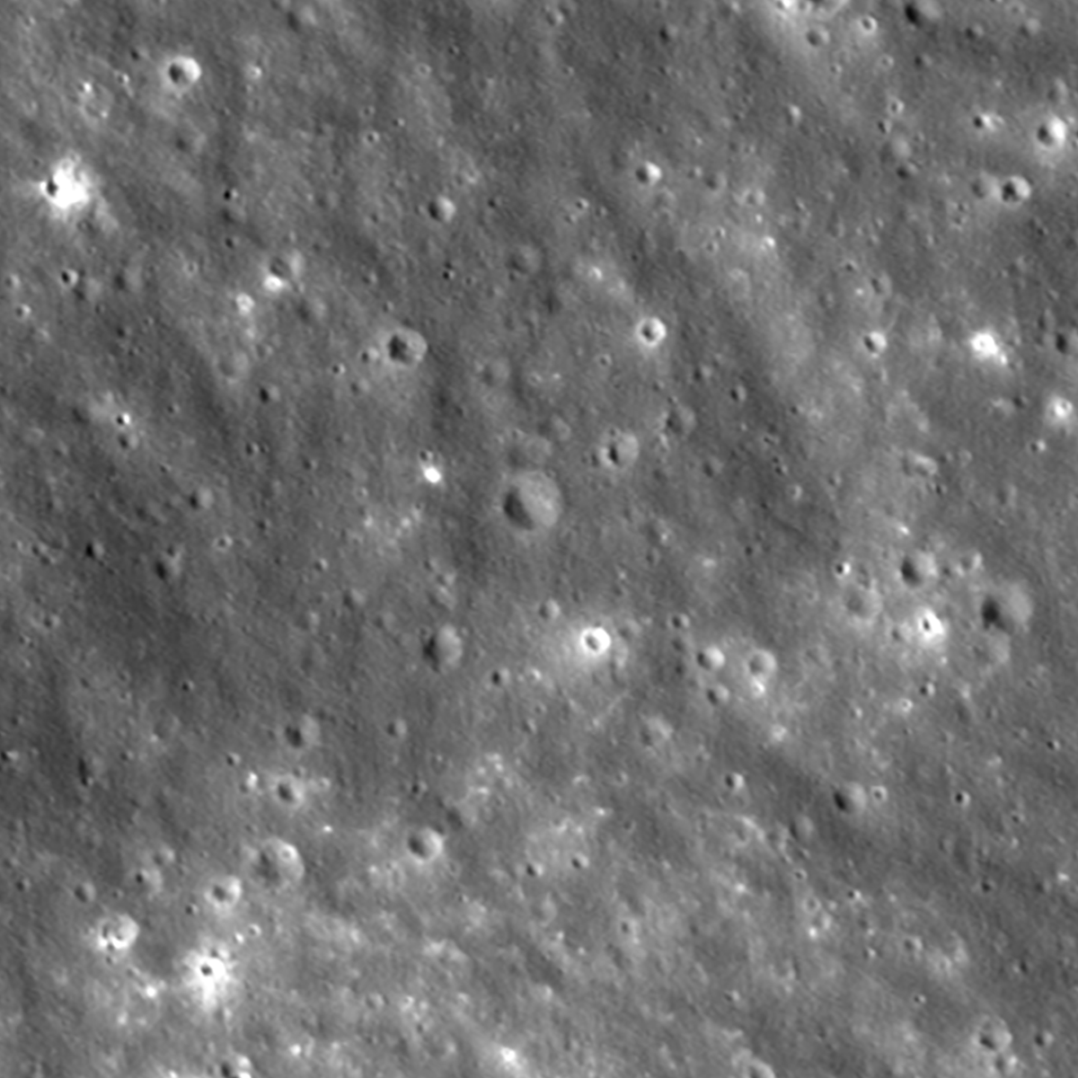 A high-angle, grayscale view of the Moon's surface, densely covered in craters of varying sizes and bright, reflective impact points.