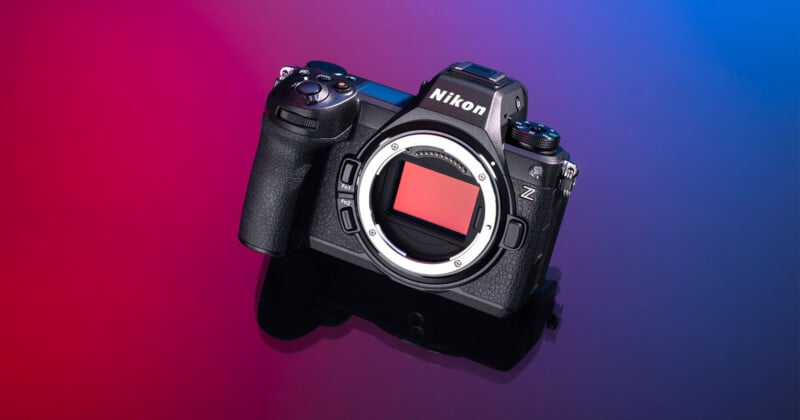A black Nikon Z-series mirrorless camera body sits on a reflective surface against a gradient background of red and blue.