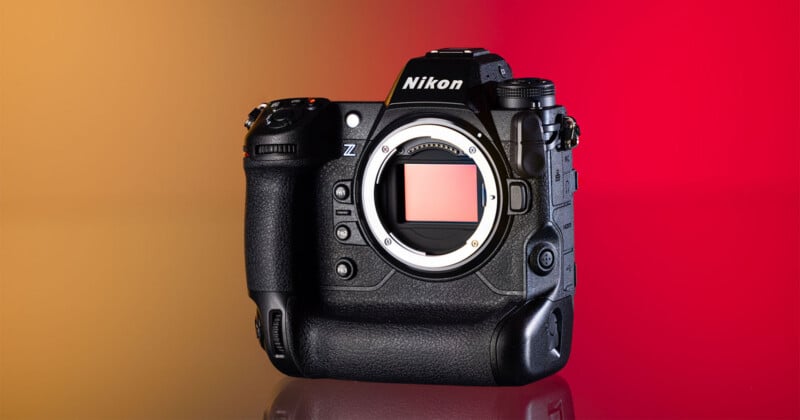 A black Nikon Z-series mirrorless camera body with a lens mount and sensor visible, set against a gradient background transitioning from orange to red.