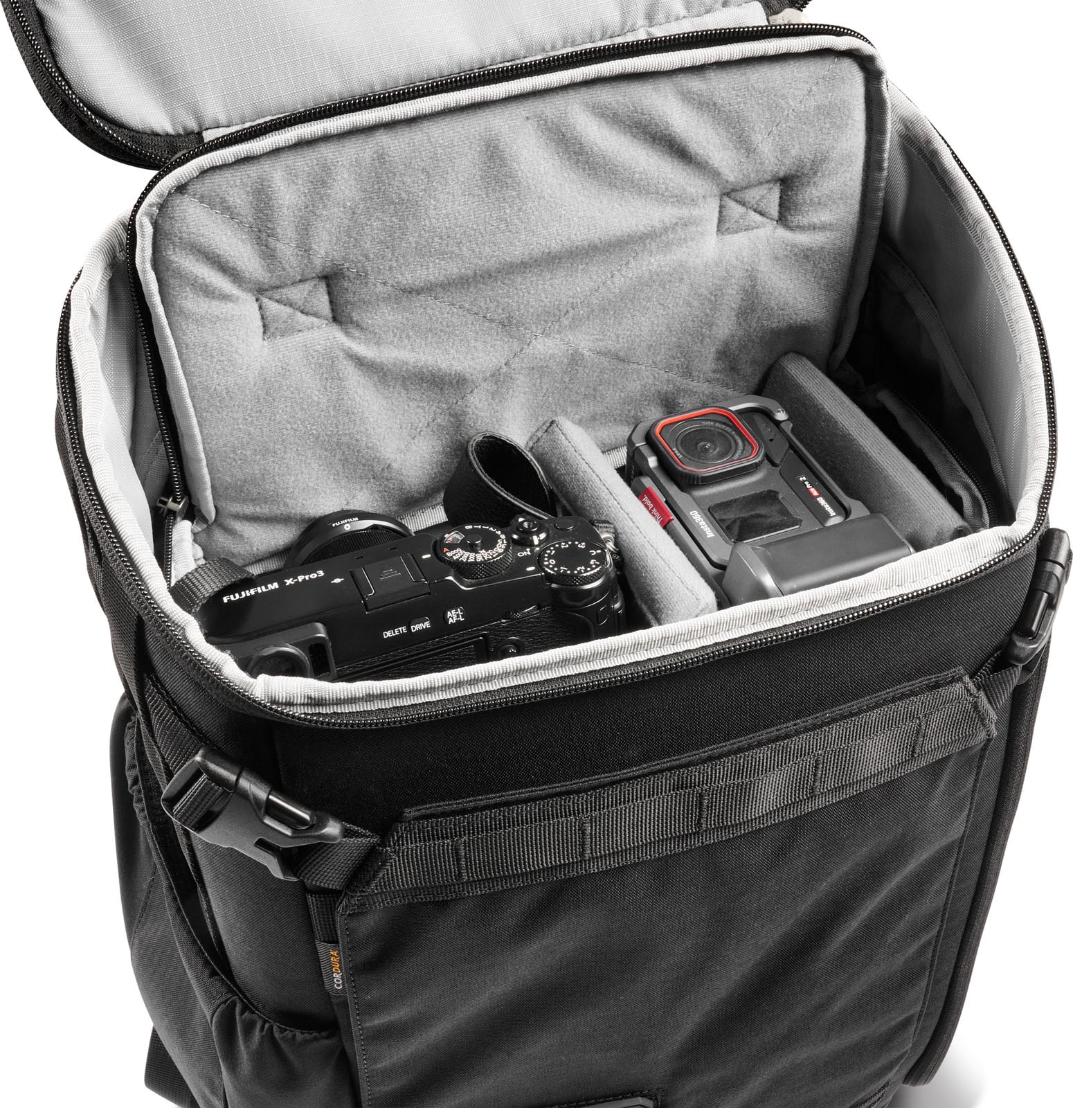 An open black camera backpack containing a Fujifilm X-Pro3 camera and an Insta360 Ace Pro 2 action camera separated by padded dividers.