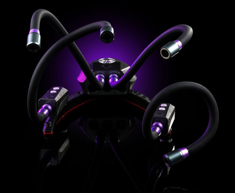 A black, multi-armed device with purple accents and control buttons sits on a reflective surface against a dark purple background.