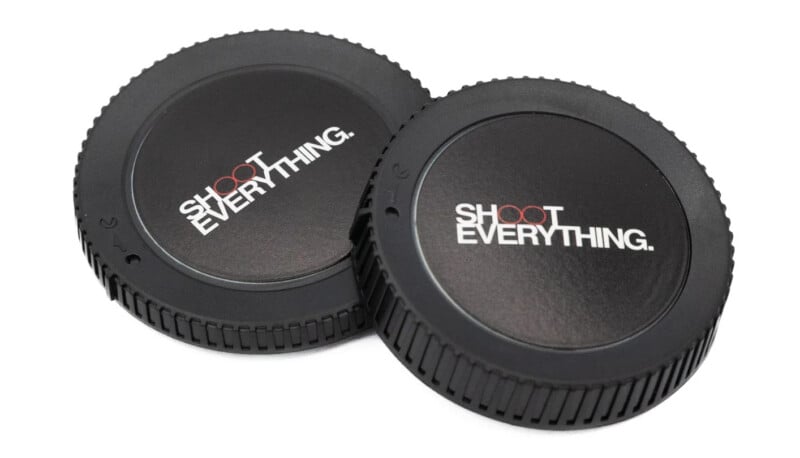 Two black camera body caps with the text "SHOOT EVERYTHING." printed in white and red on the center, resting on a white background.