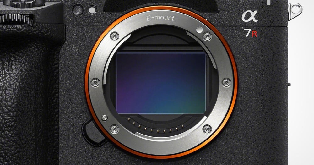 A close-up view of a camera lens mount with a visible sensor, featuring the text "E-mount" and "α 7R" on the camera body.