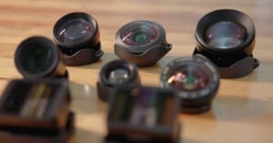 Several camera lenses and lens attachments are arranged on a wooden surface.