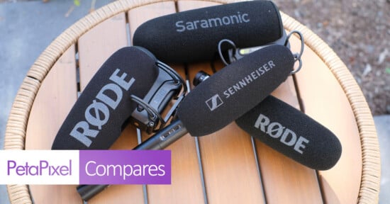 Four microphones with foam windscreens labeled Rode, Saramonic, and Sennheiser rest on a round wooden table.
