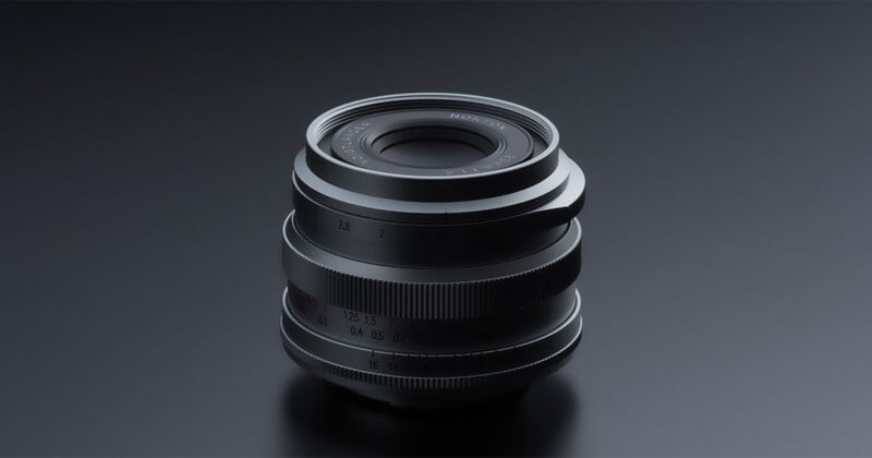 A black Voigtländer Nokton 23mm f/1.2 camera lens sits centered against a dark gray background.