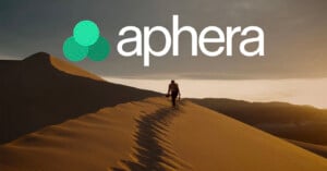 A person walks along the ridge of a sand dune at sunset, with the word "aphera" and a three-circle logo overlaid above.