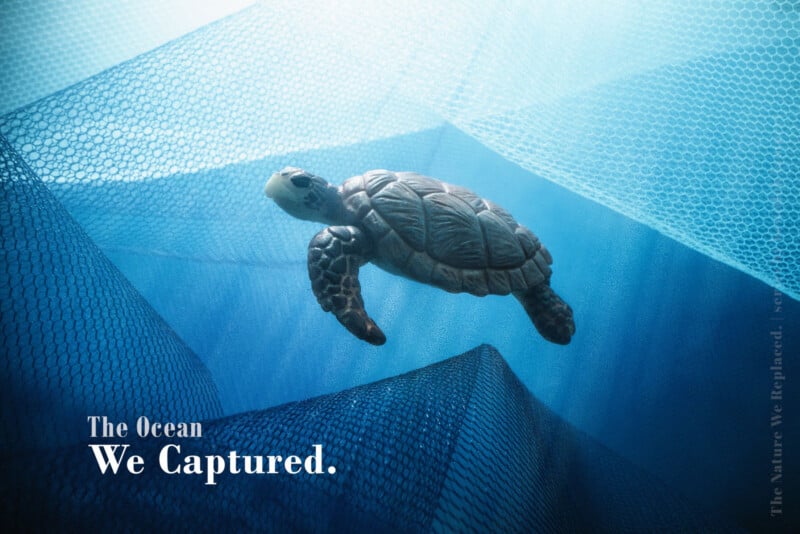 A sea turtle swims through blue fishing nets, with the text "The Ocean We Captured." in the bottom left corner.