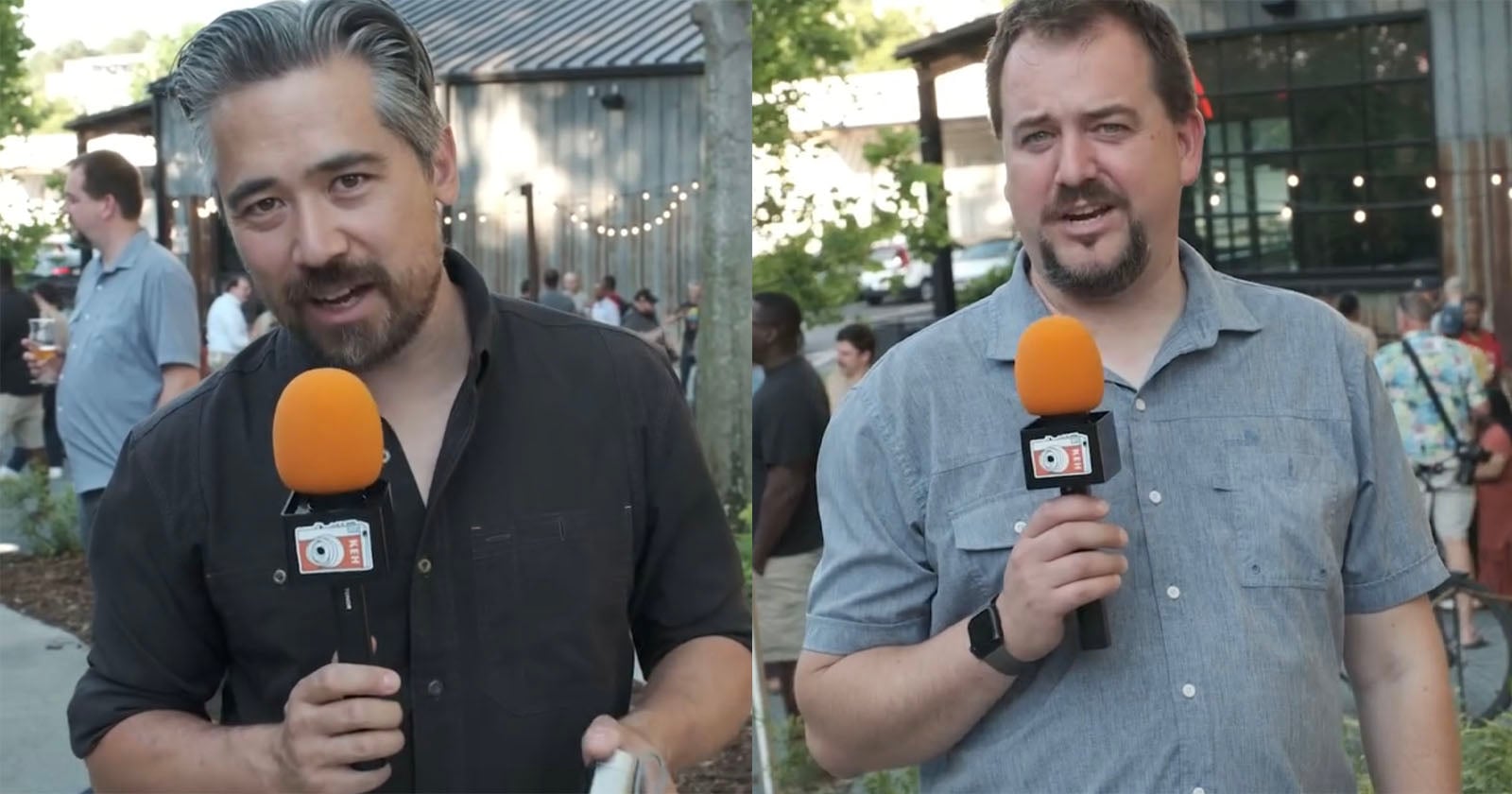 Two men stand outdoors holding microphones with orange foam covers, each featuring a small camera logo on the base.