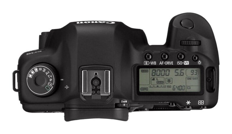 Top-down view of a black digital SLR camera body showing the mode dial, hot shoe, LCD status display, and various control buttons.