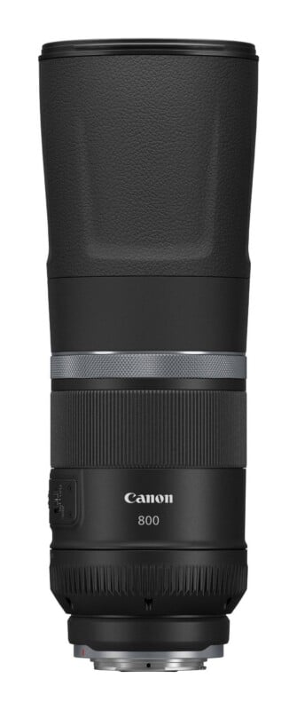 A black Canon 800mm telephoto lens stands vertically against a white background, showing its focus ring, control ring, and side switches.
