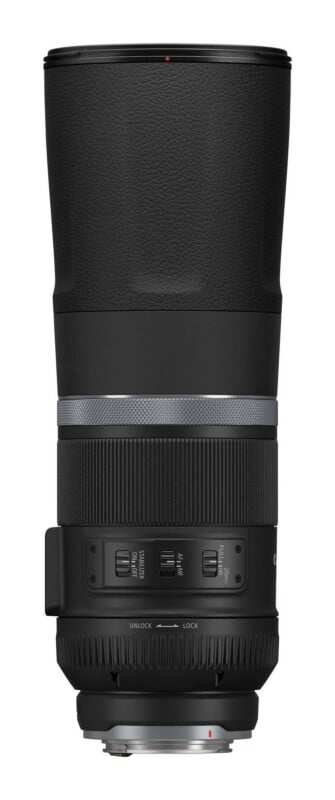 A black telephoto camera lens viewed from the side, featuring a focus ring, zoom ring, and control switches for stabilizer, focus mode, and focus range.