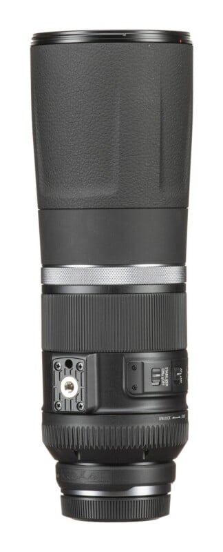A black telephoto camera lens stands vertically against a white background, featuring a tripod mount, focus and stabilizer switches, and a zoom lock ring.