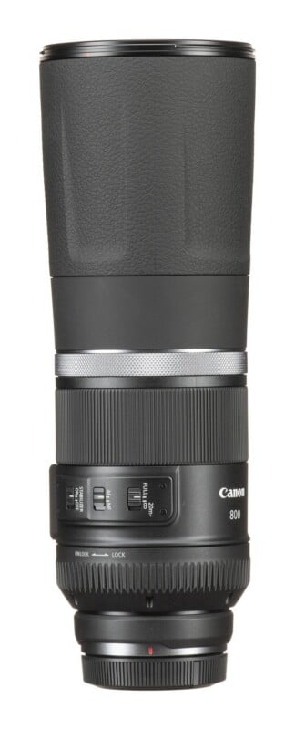A Canon 800mm telephoto lens stands vertically against a white background, featuring a focus ring, zoom lock switch, and stabilizer controls.