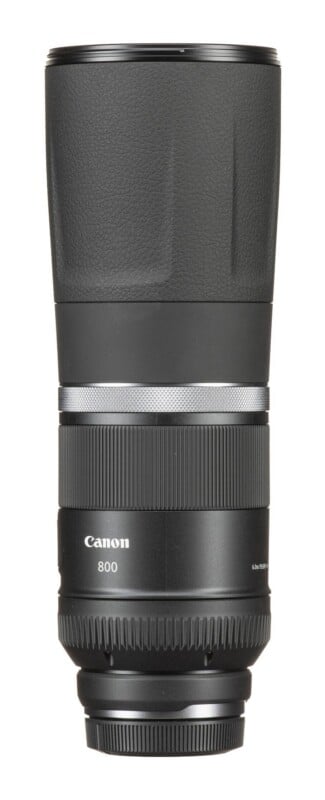 A black Canon 800mm telephoto camera lens stands vertically against a white background.
