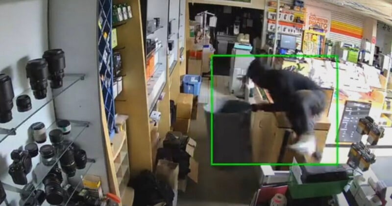 A person wearing dark clothing jumps over a counter inside a retail store, with a green box highlighting their movement.