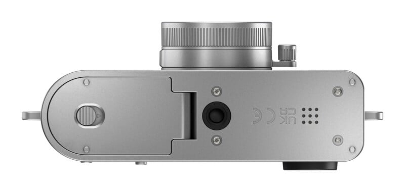 The bottom view of a silver camera shows a battery compartment door with a sliding latch, a central tripod mount, and regulatory markings including CE and UKCA logos.