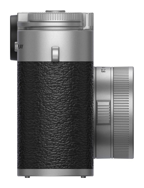 A side view of a silver and black digital camera with a textured grip, a lens barrel, and a button labeled "PLAY" on the side.