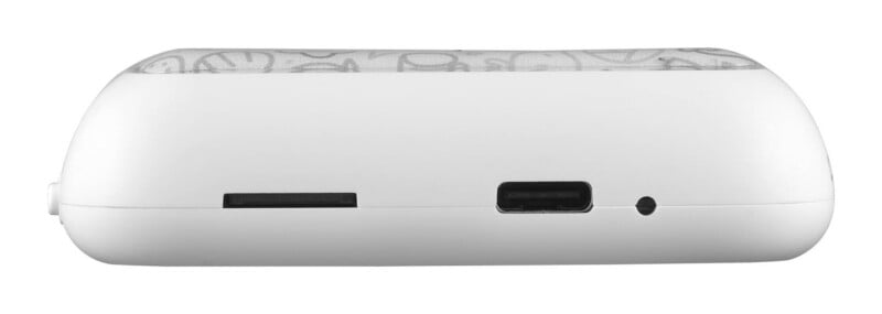A side view of a white, rounded electronic device featuring a memory card slot, a USB-C charging port, and a small circular indicator light.