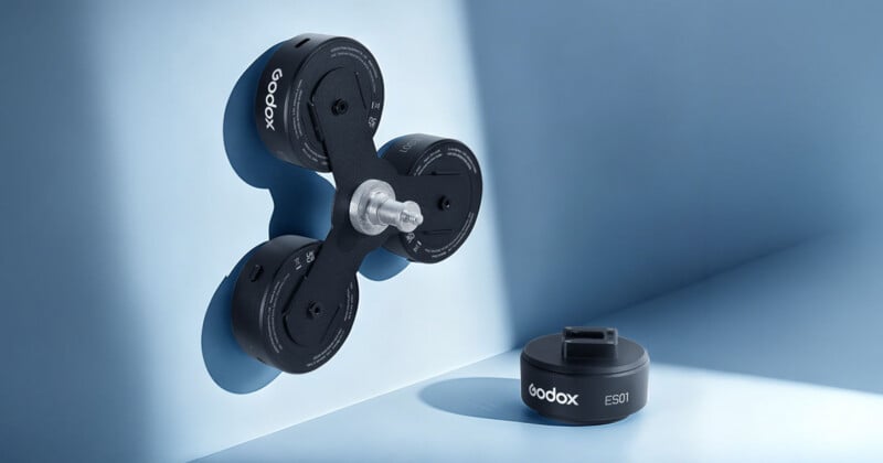 A Godox ES01 suction mount with three circular units attached to a blue wall, with a single detached unit sitting on the surface below.