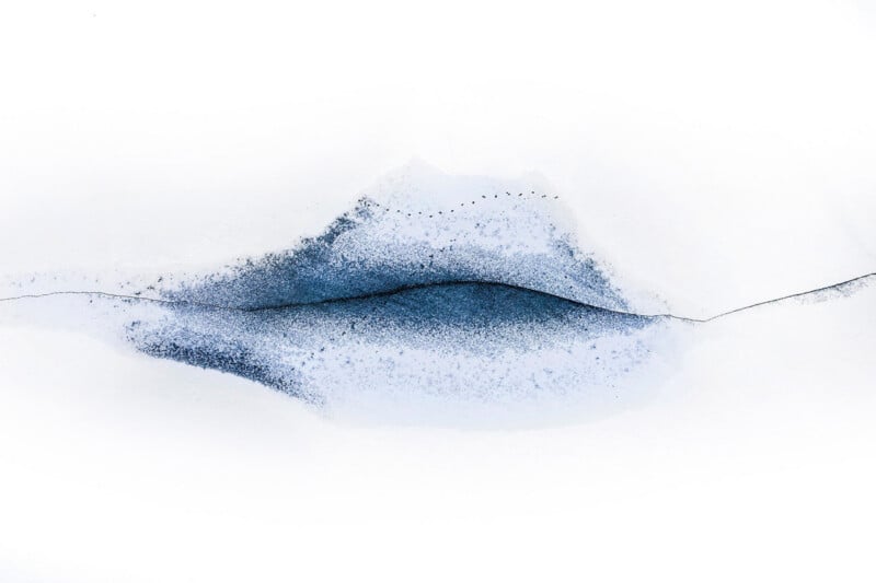 A dark, horizontal crack runs through a patch of blue-tinted snow against a stark white background, resembling the shape of lips.