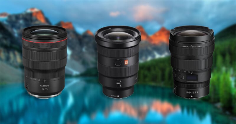 Three professional wide-angle camera lenses stand side-by-side against a blurred mountain lake background.