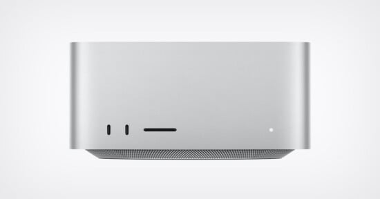 A front-facing view of a silver, rectangular desktop computer with two USB-C ports, an SD card slot, and a small status light on the front panel, sitting above a perforated base.