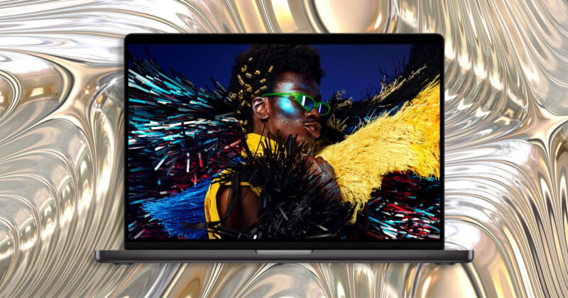 A laptop screen displays a portrait of a person with glittery makeup and bright green sunglasses against a metallic, liquid-like background.