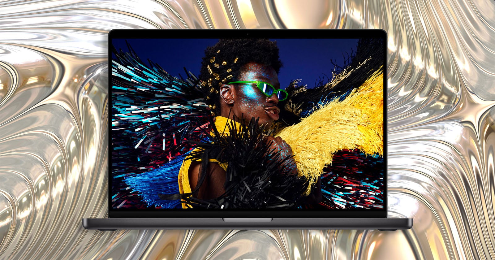 A laptop screen displays a portrait of a person with glittery makeup and bright green sunglasses against a metallic, liquid-like background.