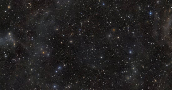 A dense field of stars and distant galaxies scattered across a dark, vast expanse of space.