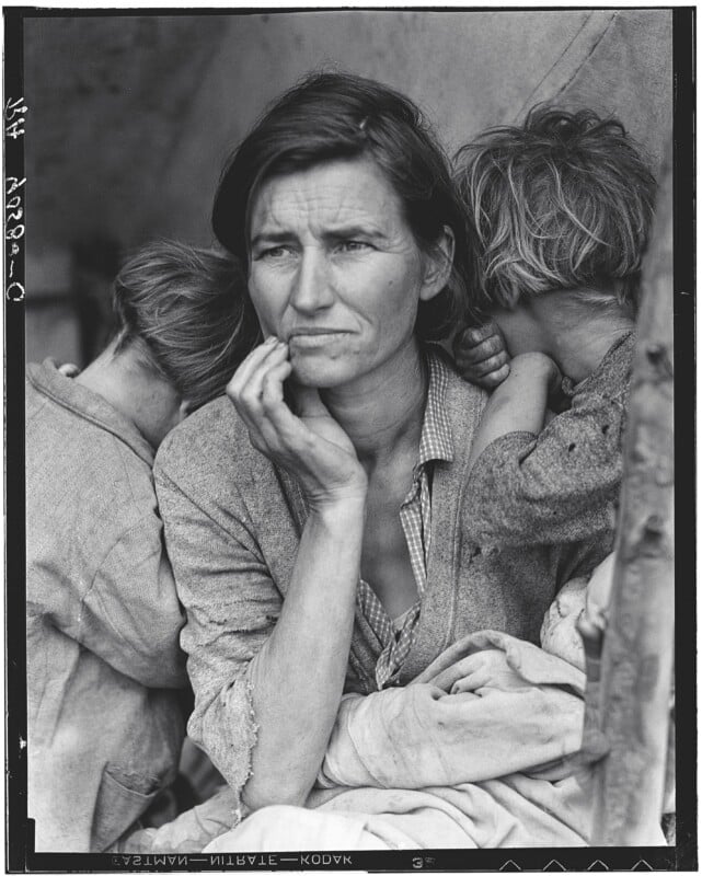 A woman with a worried expression rests her chin on her hand, surrounded by three young children who are leaning against her.