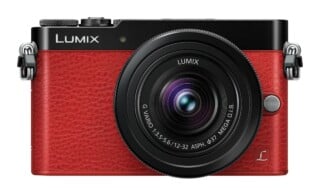 A front-facing red and black Lumix mirrorless camera with a 12-32mm lens attached.