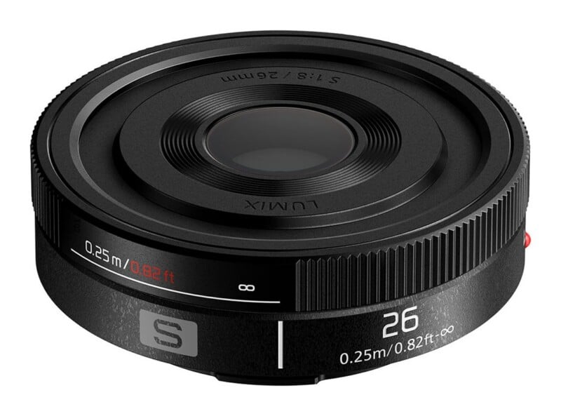 A black Lumix 26mm f/8 pancake lens viewed from a high angle, showing the focus distance markings and the S-series logo on the barrel.