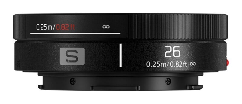 A black camera lens side view showing a focus ring with distance markings from 0.25m/0.82ft to infinity, a focal length of 26, and an S logo.