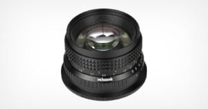 A black Pergear camera lens viewed from a high angle, showing its focus and aperture rings with white and green markings.