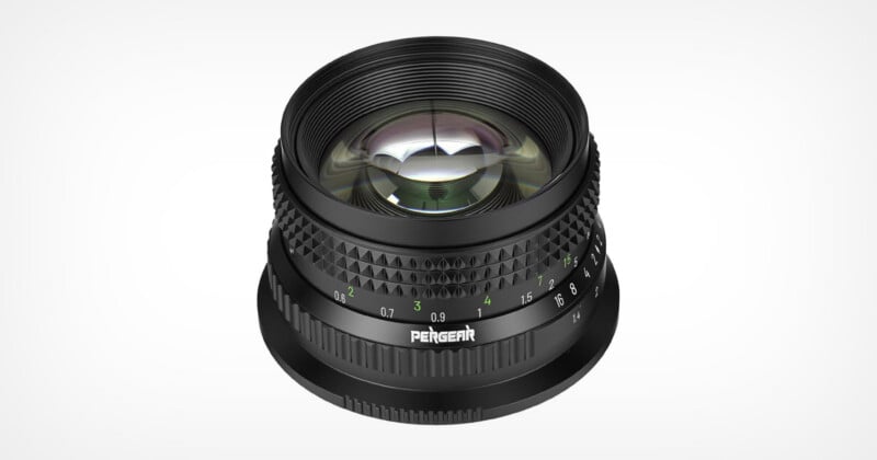 A black Pergear camera lens viewed from a high angle, showing its focus and aperture rings with white and green markings.