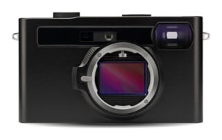 A front view of a black digital camera body with an exposed rectangular image sensor inside the lens mount.
