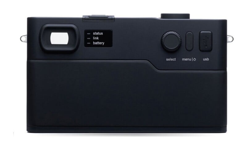 The back of a minimalist black digital camera featuring a viewfinder, a small status indicator panel, a control dial, and a USB port.