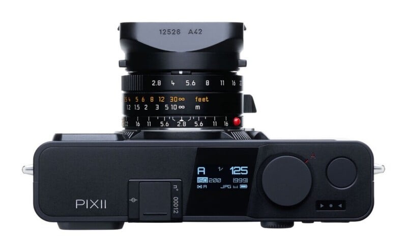 Top-down view of a black Pixii digital rangefinder camera with a lens attached, showing a digital display screen and manual aperture and focus rings.