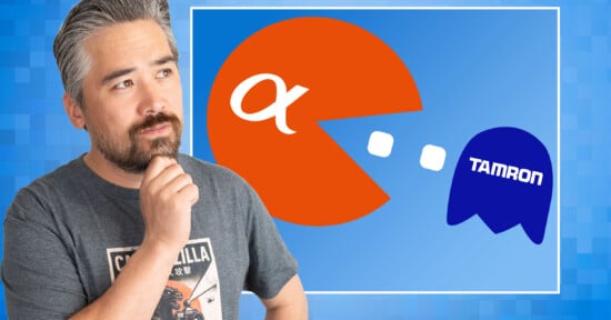 A man with a beard and graying hair rests his chin on his hand while looking at a graphic of a Sony Alpha logo styled as Pac-Man chasing a blue ghost labeled Tamron.