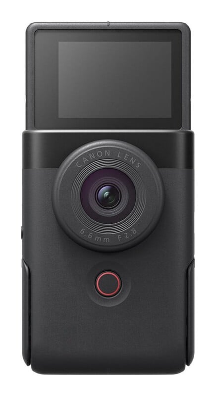 A front-facing view of a compact, black digital camera with a flip-up screen, a circular lens labeled "CANON LENS 6.6mm F2.8," and a red-ringed circular button below the lens.