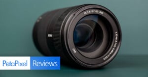 A black Sony camera lens sits on a dark green surface, with a PetaPixel Reviews logo in the bottom left corner.