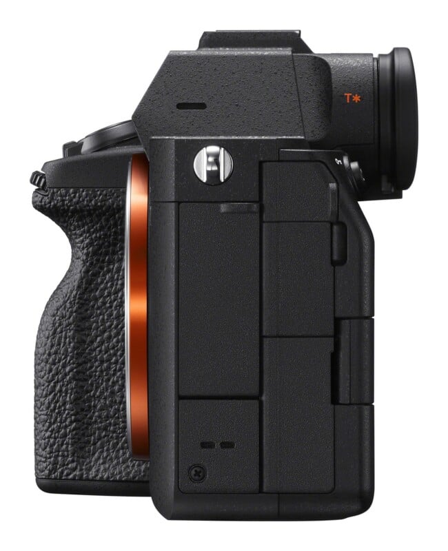 A side view of a black mirrorless camera body showing the lens mount, grip, strap lug, and electronic viewfinder with a T* logo.